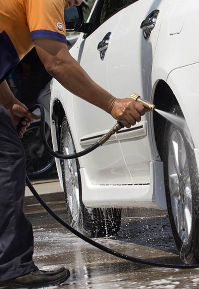Guy washing car tire with hose